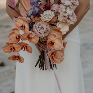 Beautiful bridal bouquet held by a woman in a white dress, photographed outdoors in Ostuni, Italy.