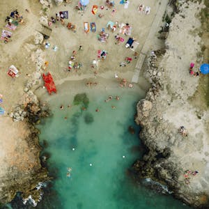 Breathtaking aerial view of Monopoli beach showcasing vibrant summer activity and emerald waters.