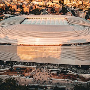 Stunning aerial shot of the Santiago Bernabéu Stadium, Madrid during sunset with bustling cityscape.